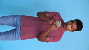 Young man using cell phone in studio shot. Vertical video.