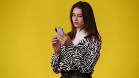 4k video of one girl who using the phone over yellow background.