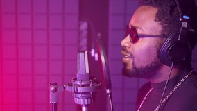 Slow motion close-up shot of an African American singer recording a song in professional music studio. Musician closing eyes being alive with emotion - Powered by Shutterstock - Get 15% off with code: PIKWIZARD15