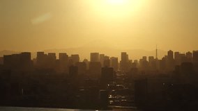 TOKYO, JAPAN : Sunset aerial time lapse shot of cityscape of Tokyo and Mount Fuji. View of buildings at downtown area. Japanese urban metropolis, nature and travel concept 4K video.