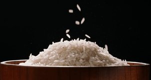Rice being poured raw wooden cup side view black background 4K footage. Pouring rice grains 4K video on a dark background. Asian Japanese Indian ethnicities culture healthy food. Still life relax