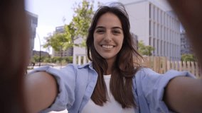 Cheerful young Caucasian female influencer recording selfie video for social media followers. Natural beautiful girl in casual and positive attire using mobile phone outdoors to share online content.  - Powered by Shutterstock - Get 15% off with code: PIKWIZARD15