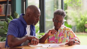 Senior couple sitting around table at home with bills reviewing domestic finances - shot in slow motion - Powered by Shutterstock - Get 15% off with code: PIKWIZARD15