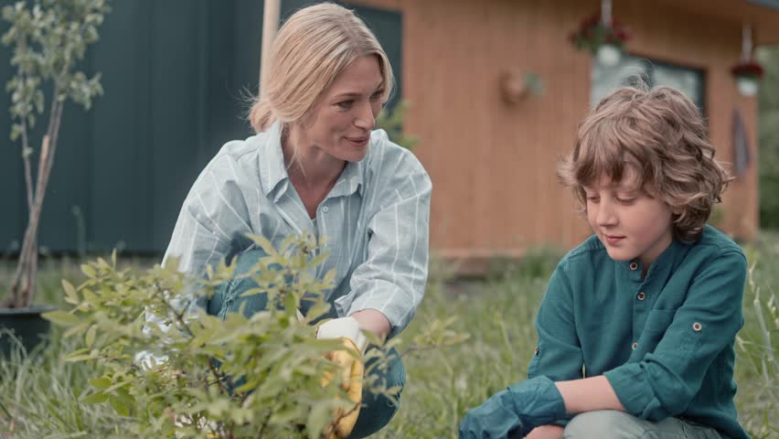 Beautiful mother having positive conversation with her son. Showing gardening process to her kid. Supporting each other. Caring about nature. Family connection. Concept of relationship.