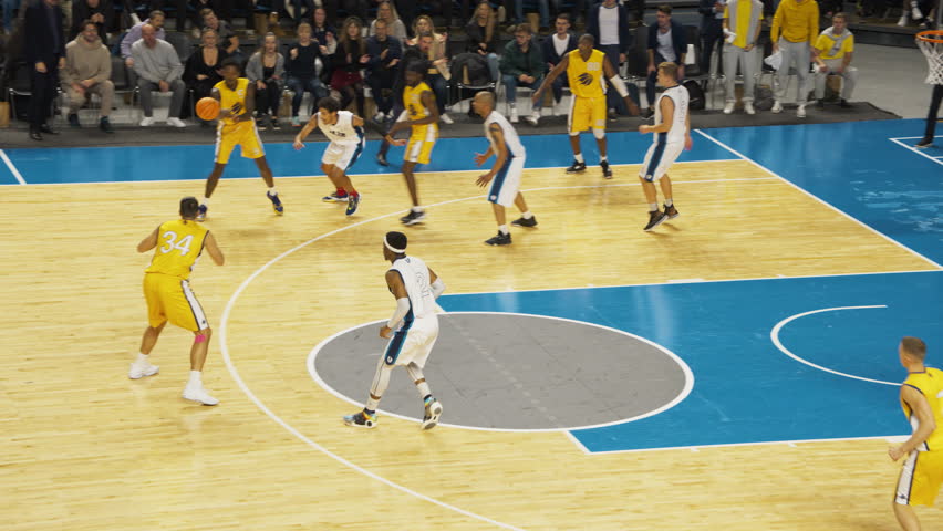 Slow Motion Replay of a Basketball Match in an Arena. Yellow Team Passing the Ball Between Teammates, Forward Player Scoring a Two-Point Goal From a Distance. Sport TV Channel Broadcast Playback
