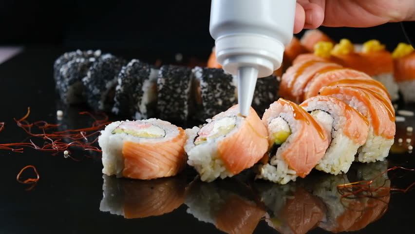 The chef pours sauce over sushi in a Japanese restaurant. Professional preparation of traditional Japanese food - sushi. Royalty-Free Stock Footage #1105237055