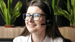 A young smiling woman in headphones works in a technical support service. Helpful customer support call center. virtual team meeting via videoconference