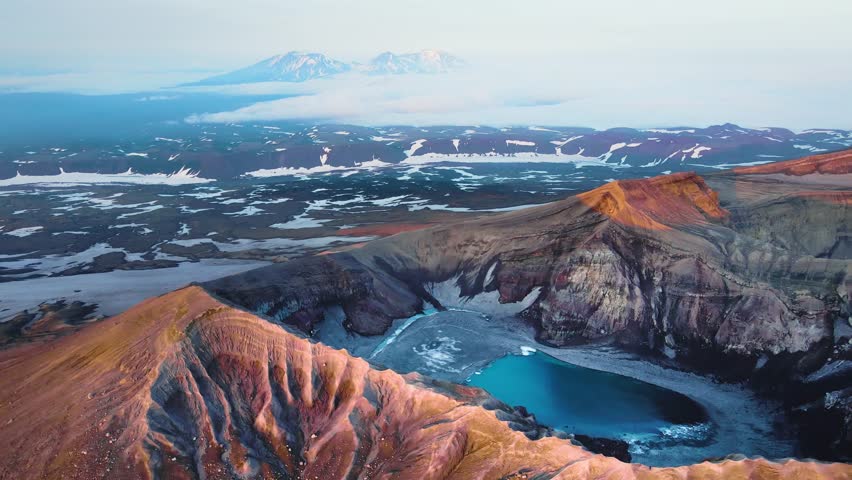 Gorely volcano crater with blue lake in Kamchatka, Russia. Aerial view. Mountains and volcanoes with clouds at sunrise. Beautiful summer landscape
 Royalty-Free Stock Footage #1105238245