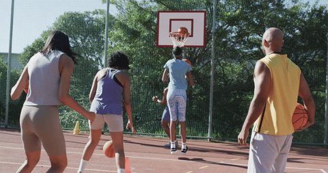 Happy diverse female basketball team training with male coach on sunny court, in slow motion. Sport, fitness, health and outdoor activities, unaltered., videoclip de stoc