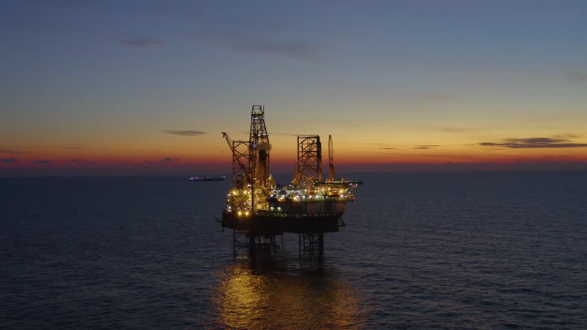Aerial view of offshore jack up drilling rig during early night time - oil and gas industry Royalty-Free Stock Footage #1105245823