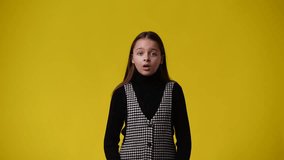 4k video of one girl who doubts and waving his hands around over yellow background.