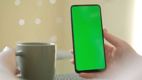 Women sittihg on table using smartphone with chroma key green screen , scrolling through social media or online shop - internet, communications concept close up 4k template
