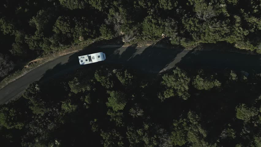 Aerial Shot, White Motorhome Van Drives the Green Wooded Hills Road, Southern France, Drone Bird's Eye View Royalty-Free Stock Footage #1105255313