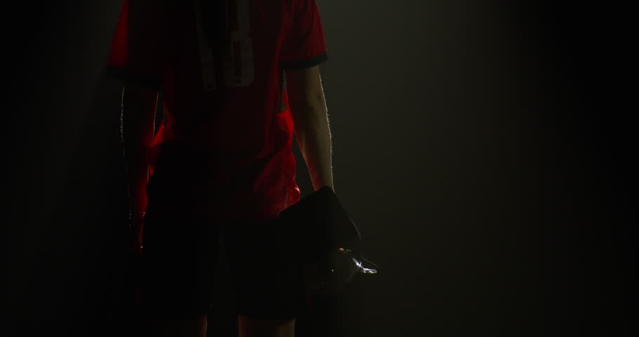 Silhouette of Caucasian woman female soccer football player raising a trophy above head against bright light and falling confetti. Super slow motion, shot on RED cinema camera