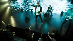 Jib shot of a rock band playing the gig during concert on stage of a large venue, surrounded by bright flashing stage lights - Powered by Shutterstock - Get 15% off with code: PIKWIZARD15