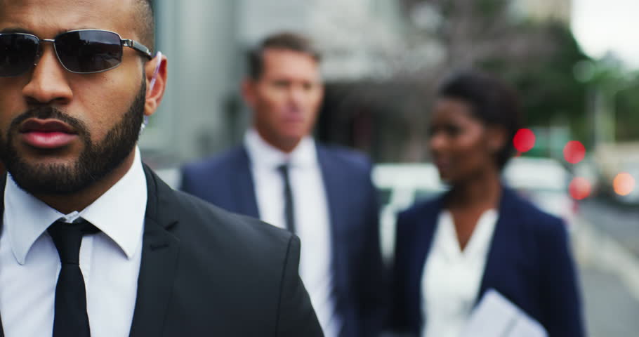 Serious African security guard and business people outdoor with protection for urban career. Bodyguard, walking and escort on street with sunglasses to protect professional in city with executives. Royalty-Free Stock Footage #1105265357