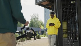 Backstage. Operator takes video of young african man in yellow headphones and yellow hoodie with phone in his hands. Slow motion