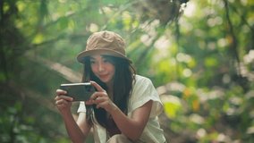 Young tourist asian woman using smartphone taking photo and video in forest nature with sunlight, Female blogger making digital content using mobile phone, Rest on vacation holiday weekend
