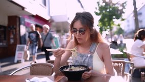 Woman eating a bowl of beef noodles in an asian restaurant with chopsticks.Eating Chinese  soup dish consisting of noodles, herbs, and meat.Vietnamese beef noodle pho soup, phở.