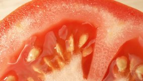 A mesmerizing macro video showcases a half tomato, its vibrant red flesh and seeds vividly revealed through a specialized probe lens. An up-close exploration of nature's intricate details. 4K UHD
