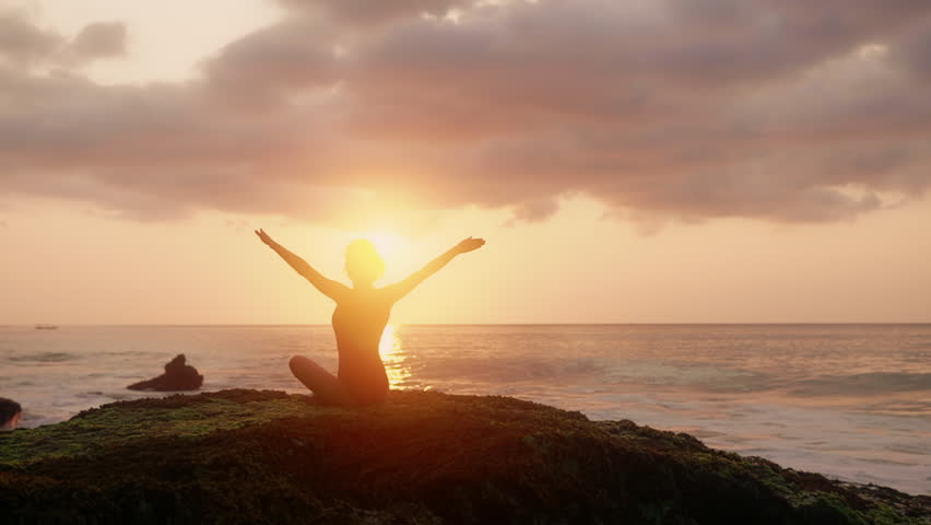 Pretty brunette woman Person meditate in front of orange sunset. Silhouette of young woman doing yoga exercises. Girl in red swimsuit relaxing on the ocean coast. Concept of health, relax, yoga. Royalty-Free Stock Footage #1105273233
