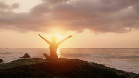 Pretty brunette woman Person meditate in front of orange sunset. Silhouette of young woman doing yoga exercises. Girl in red swimsuit relaxing on the ocean coast. Concept of health, relax, yoga. - Powered by Shutterstock - Get 15% off with code: PIKWIZARD15