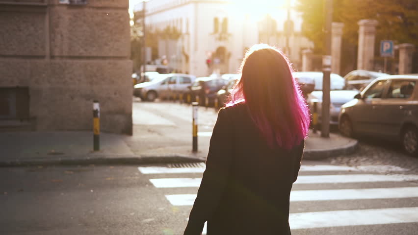 Cute Asian hipster runs along the sidewalk and eats ice cream. Hipster, beauty, fashion, travel, millenial concept. A pretty girl with pink hair poses against the background of a sunny street.