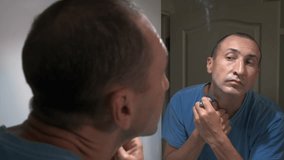 Daily hygiene of the male face. A forty-year-old man shaves his face with a razor while looking in the mirror. - Powered by Shutterstock - Get 15% off with code: PIKWIZARD15