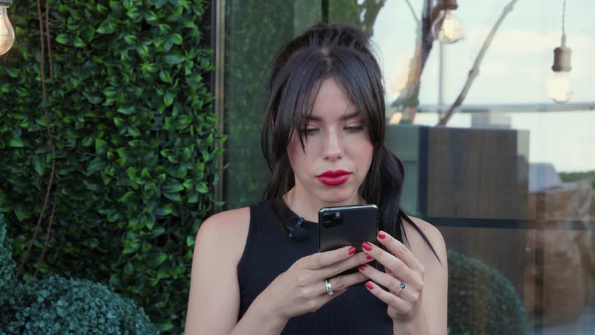 Beautiful woman in black clothes holding a phone, relaxing, chatting with friends on a smartphone