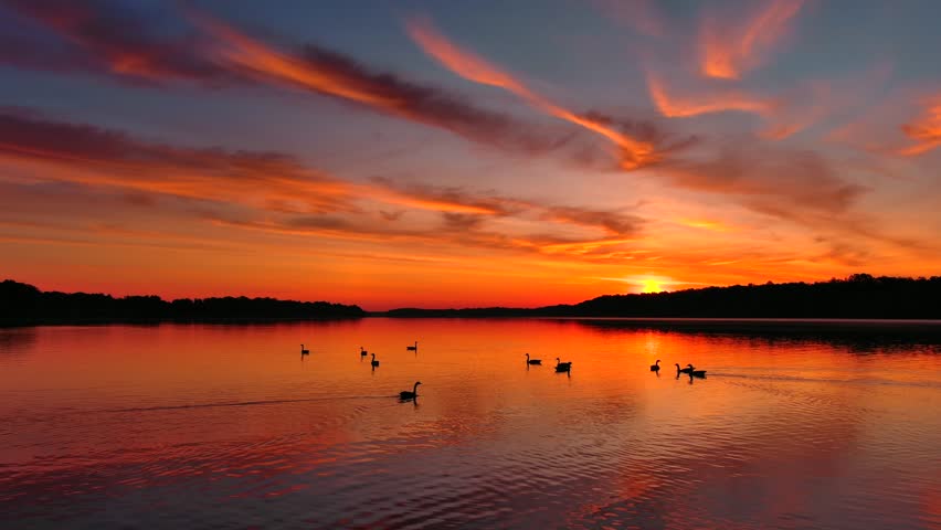 Incredible red dawn sky reflected in tranquil waters, this is the Fox River in Wisconsin, moving aerial perspective