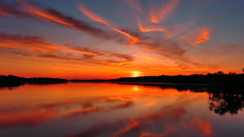 Incredible red dawn sky reflected in tranquil waters, this is the Fox River in Wisconsin, moving aerial perspective