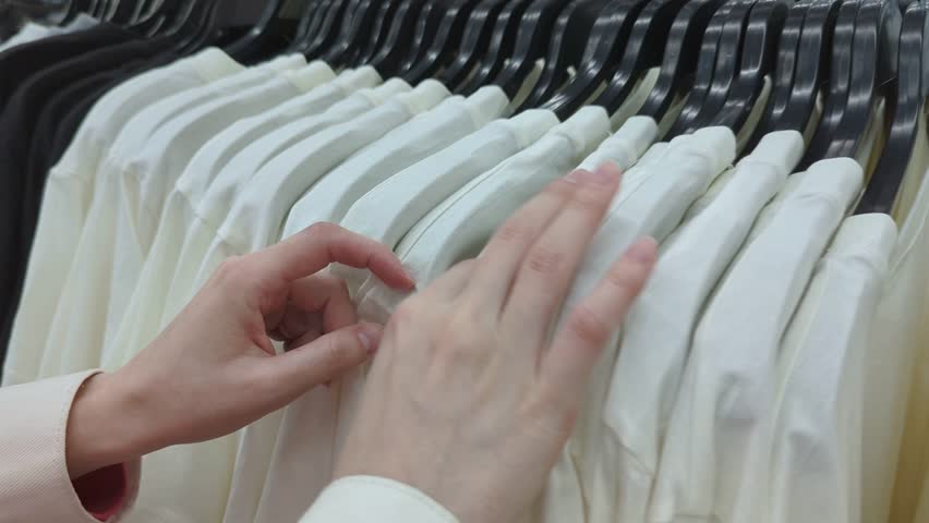 Close up footage of Woman is choosing Clothes in shop with T-Shirts. Shopping day and sale.
