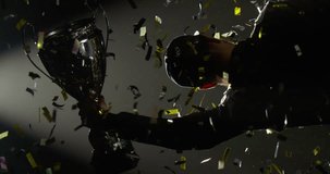 VERTICAL VIDEO - Silhouette of race car driver celebrating the win in a race against bright stadium lights, rising a trophy over his head