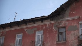 Old residential building. Clip. Close-up view of shabby facade of old residential building. Crumbling facade of old apartment building on background sky
