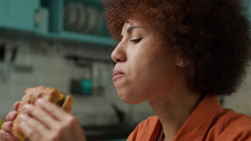 Black Woman Eating Burger. Female Biting Yummy Cheeseburger Close Up Slow motion. Royalty-Free Stock Footage #1105288949