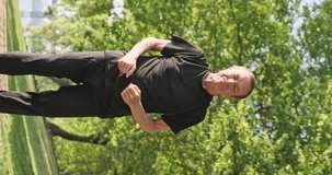 Qigong wu qin xi, five animal games, deer, rejuvenating exercises. Man practices yoga in city park. Vertical video