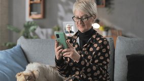elderly stylish woman sits on couch at home using smartphone searching for love online on dating application,augmented reality - Powered by Shutterstock - Get 15% off with code: PIKWIZARD15