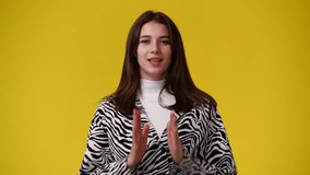4k video of one girl claps his hands and smiling over yellow background.