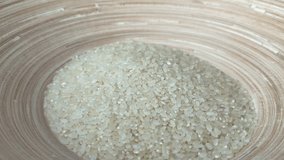 Japanese raw rice grain for sushi or risotto falling into a bamboo bowl.Wholegrain cereals. Concept of healthy lifestyle, clean eating, dieting.