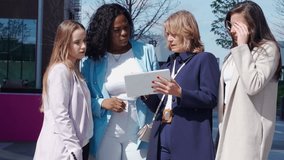 Group of female executives gathering outdoors to review business statistics and data on digital tablet - Powered by Shutterstock - Get 15% off with code: PIKWIZARD15