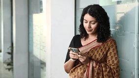 Stock video of Woman Employee In Saree in office break time showing smart phone screen on camera
