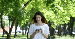 Young beautiful girl with a mobile phone in a summer park