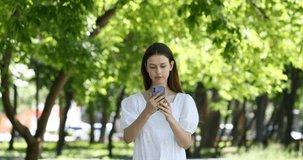 Young beautiful girl with a mobile phone in a summer park