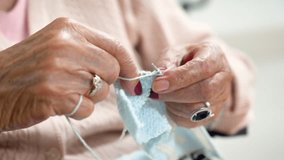 Elderly woman crocheting in a handicraft course as a hobby or occupational therapy at nursing home. High quality 4k footage