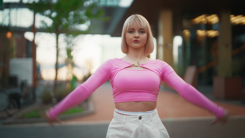 Following Shot Of Beautiful And Fashionable Young Caucasian Woman Wearing Pink Outfit And Voguing On City Street. Vogue Dancer Practicing Choreography During The Day. Preparing For The Vogue Ball.