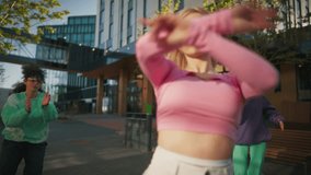 Close Up Shot of Fashionable Young Woman Wearing Pink Outfit Voguing On City Street In Circle Of Stylish Friends. Group Of Young People Supporting Female Vogue Dancer, Filming Her On The Smartphone
