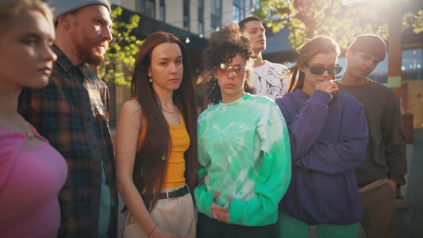 Group Of Young And Stylish Men And Women Posing And Looking At Camera In Slo-Mo. Male And Female Fashionable Friends Representing Youth Subcultures. Creative People Hanging Out Together Downtown.