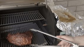 This video shows a large smoked brisket being taken out of a smoker grill with tongs.