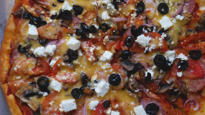 close-up big round appetizing pizza with cheese, onions, bacon rotates .macro pizza on a platter.pizzeria concept