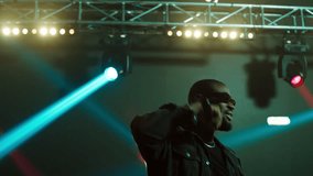 African-American Black rap artist performing his gig on a stage of a large venue, surrounded by bright flashig lights - Powered by Shutterstock - Get 15% off with code: PIKWIZARD15